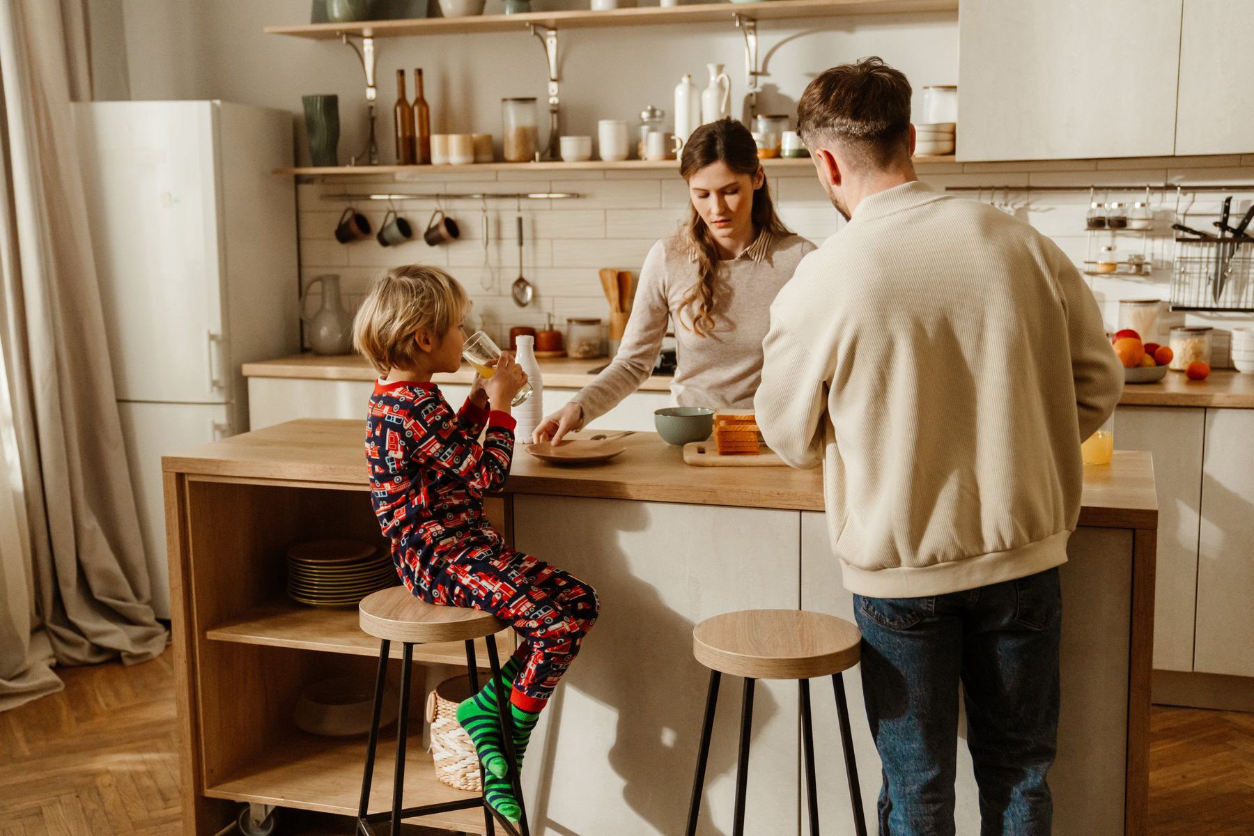 Familie beim Frühstück in der Küche, das Kind sitzt im Schlafanzug am Tresen
