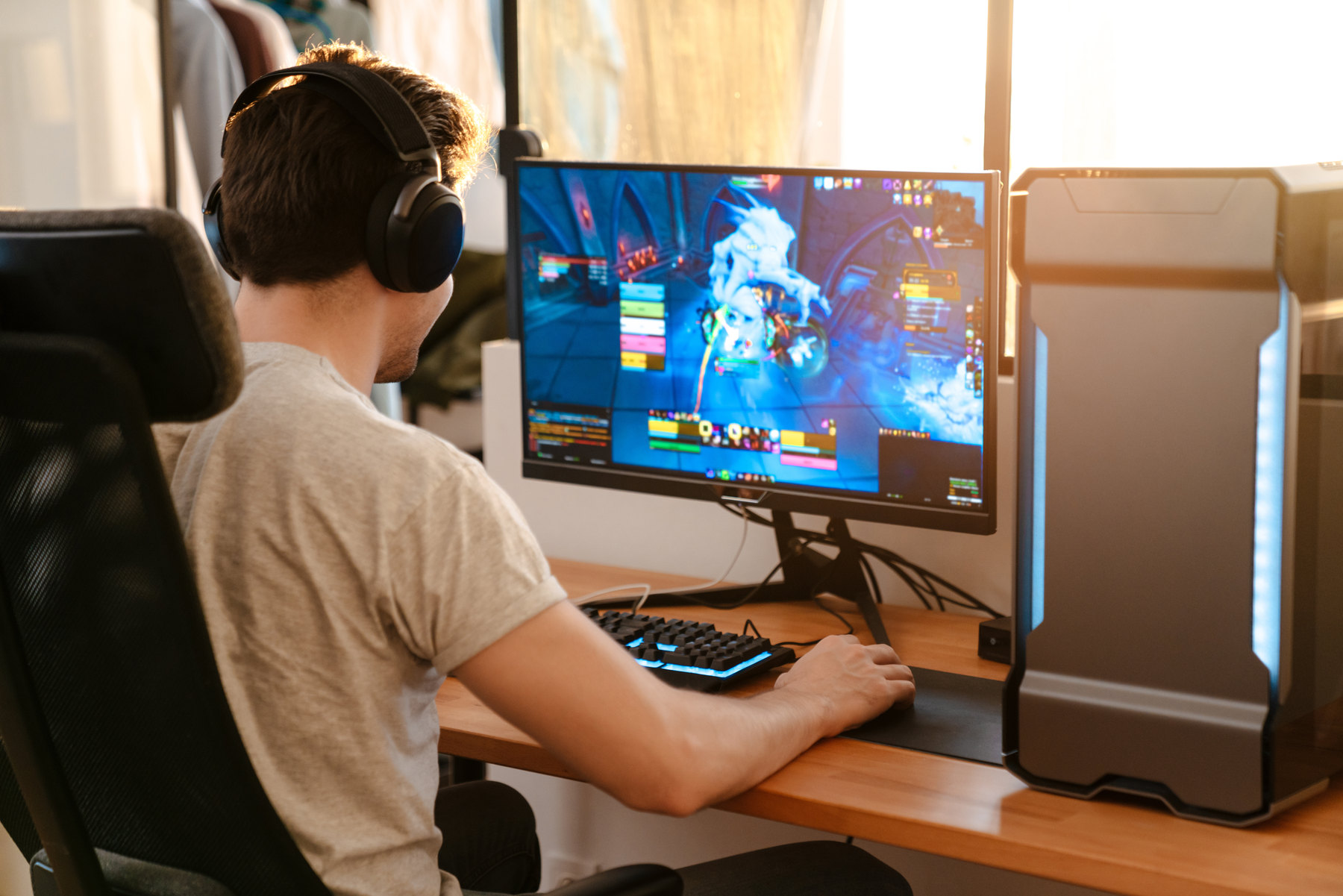 Jugendlicher mit Kopfh&ouml;rern spielt am Schreibtisch ein Computerspiel
