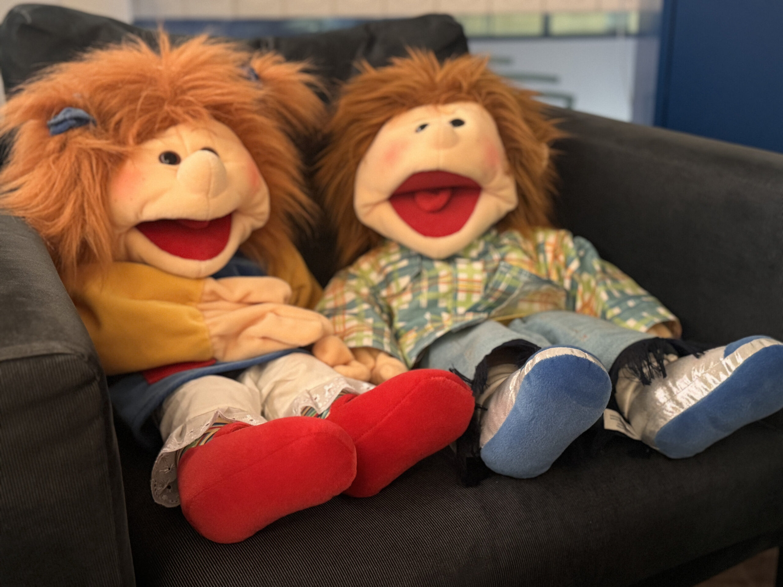 Zwei Handpuppen sitzen nebeneinander auf dem Sofa