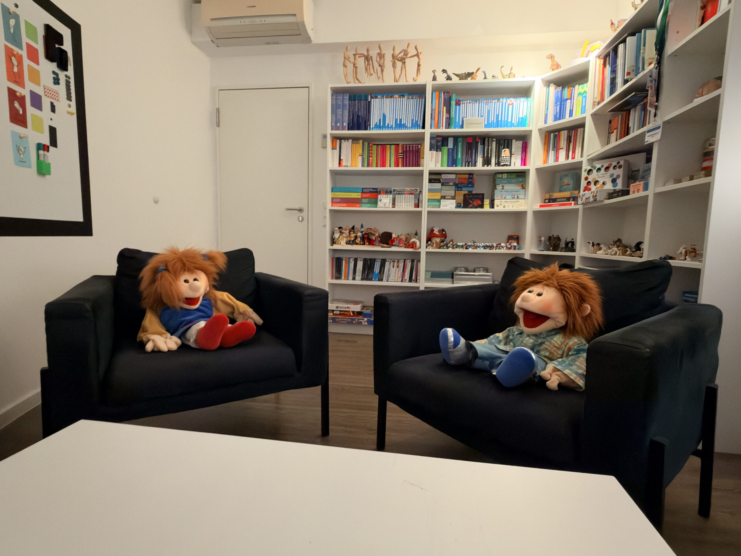 Zwei Sessel mit Handpuppen vor der B&uuml;cherwand