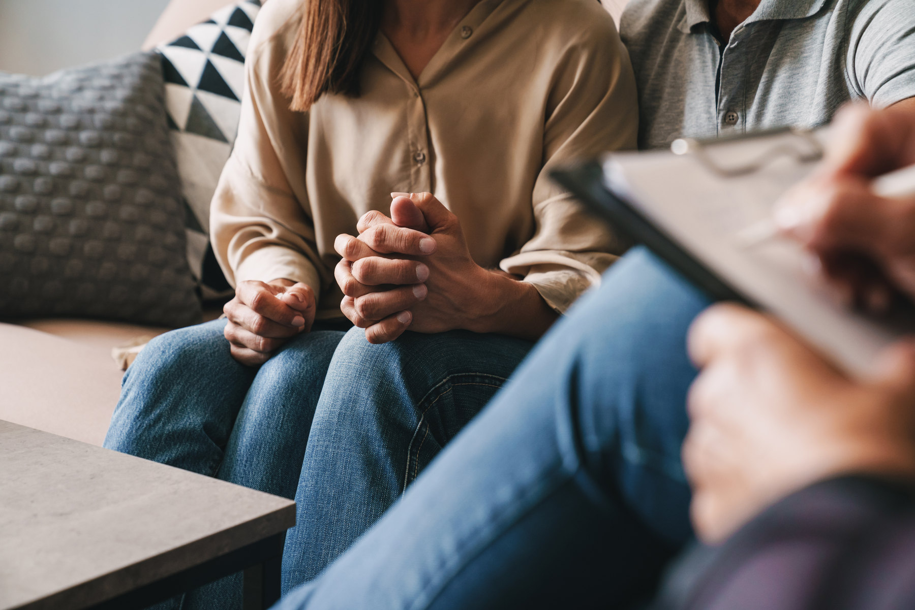Paar im Gespräch auf einem Sofa, gegenüber eine Person mit Klemmbrett